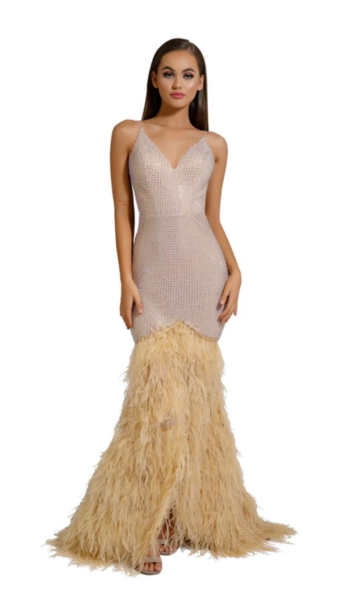 A woman wears the Portia and Scarlett Long Formal Dress PS6826, a sleeveless mermaid gown with a sparkling beaded bodice, v-neckline, and flared skirt with light beige feather trim, standing against a plain white background.